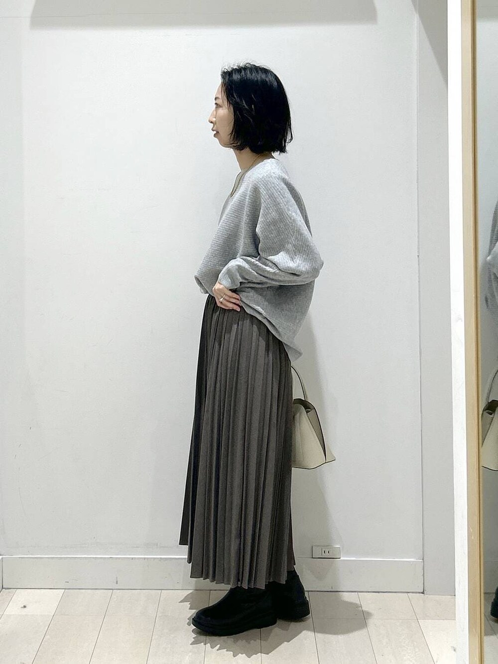 ホワイト系のショルダーバッグ、ブラック系のブーツ、グレー系のスカートを着用したレディースの冬コーディネートの4枚目の写真