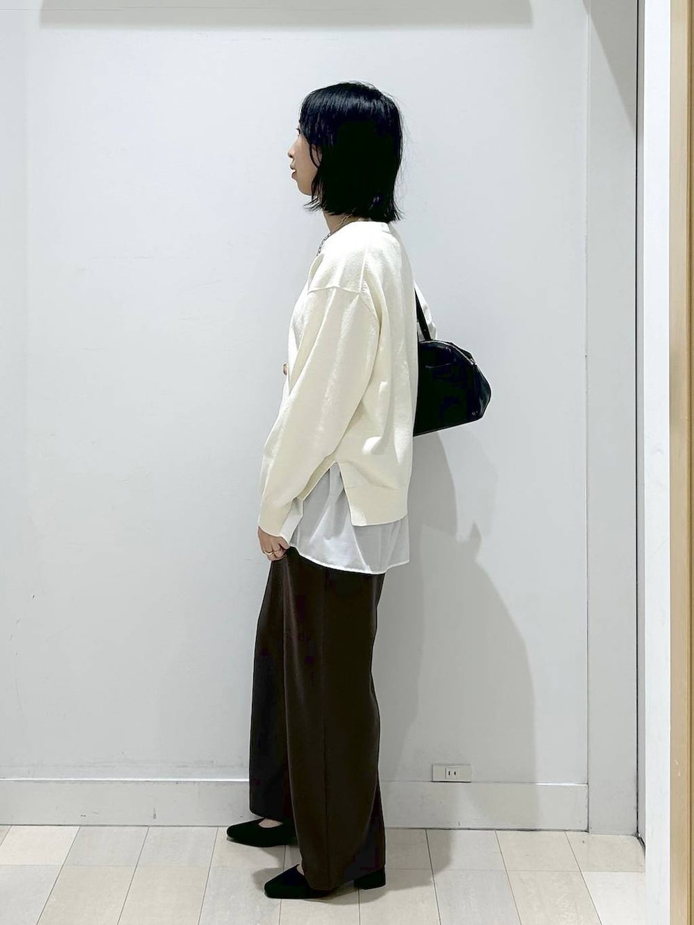 ベージュ系のニット/セーター、ブラウン系のその他パンツ、ホワイト系のタンクトップを着用したレディースの春コーディネートの2枚目の写真