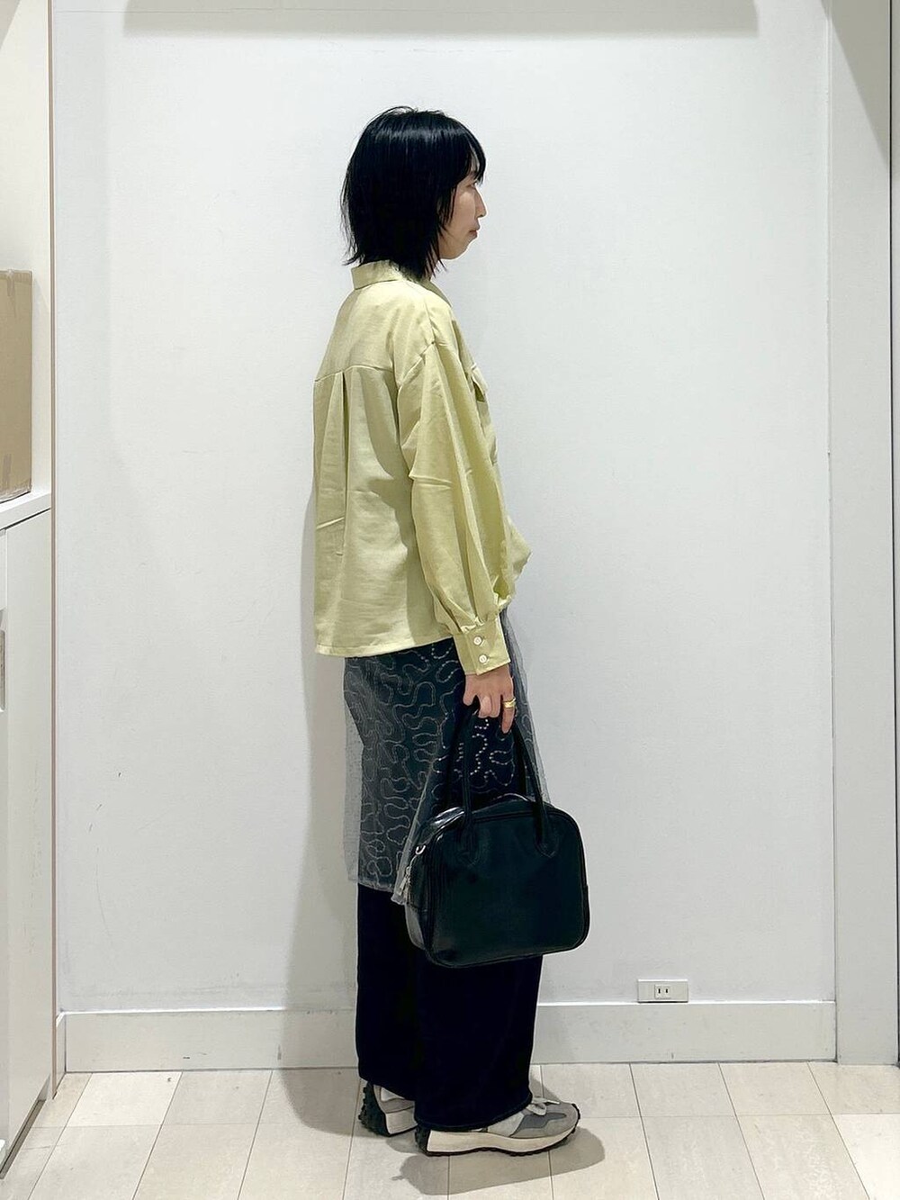 ブルー系のデニムパンツ、ブラック系のボストンバッグ、イエロー系のシャツ/ブラウスを着用したレディースの春コーディネートの2枚目の写真