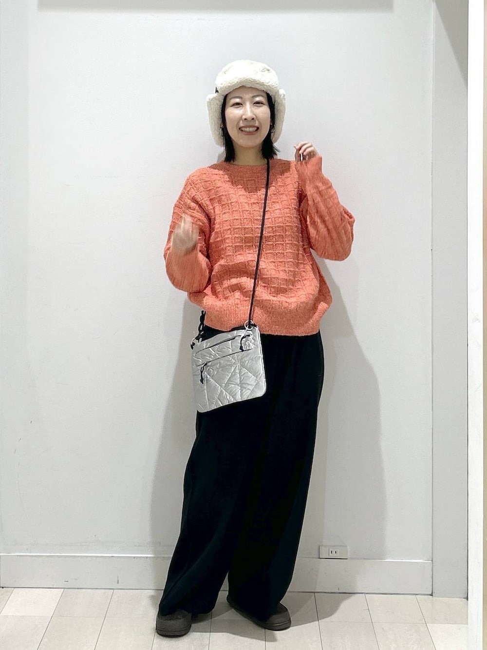 オレンジ系のニット/セーター、ブラック系のその他パンツ、グレー系のショルダーバッグを着用したレディースの冬コーディネートの5枚目の写真