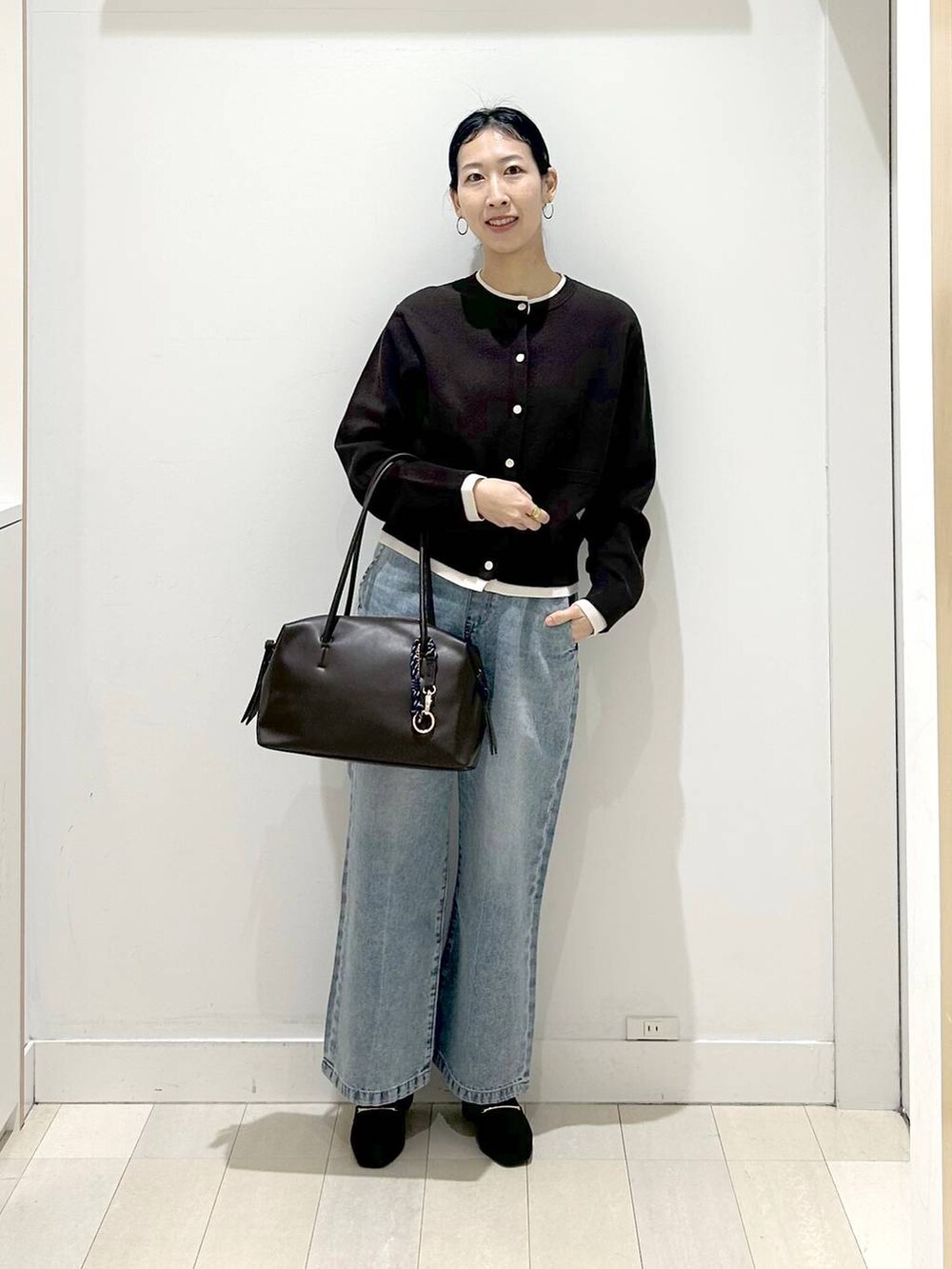 ブラック系のローファー、ブラック系のボストンバッグ、ブルー系のデニムパンツを着用したレディースの春コーディネートの5枚目の写真