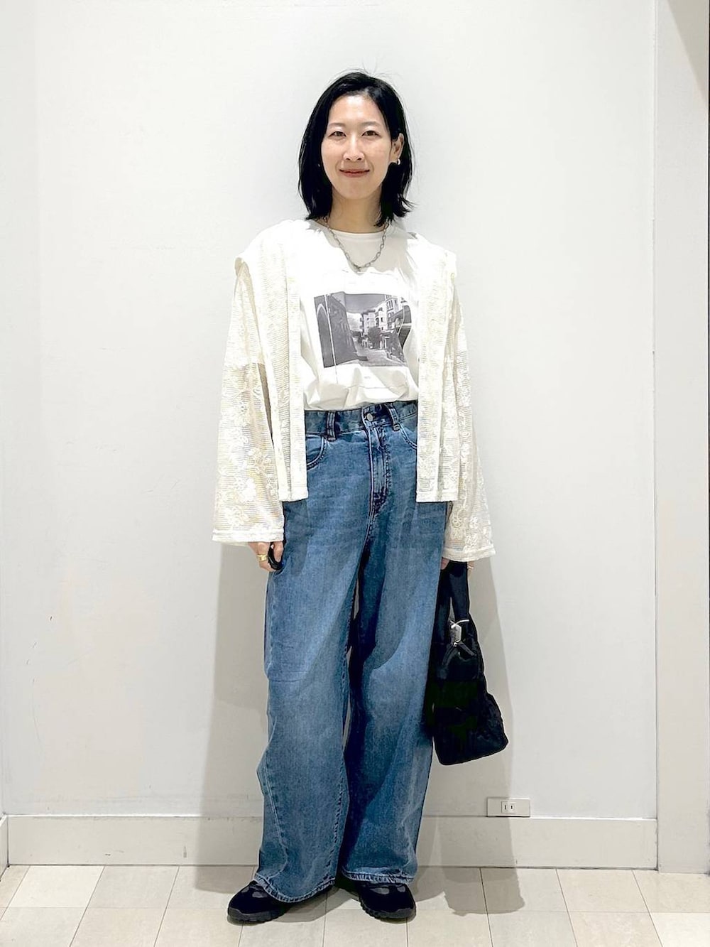 ブラック系のトートバッグ、ブルー系のデニムパンツ、ベージュ系のパーカーを着用したレディースの春コーディネートの5枚目の写真