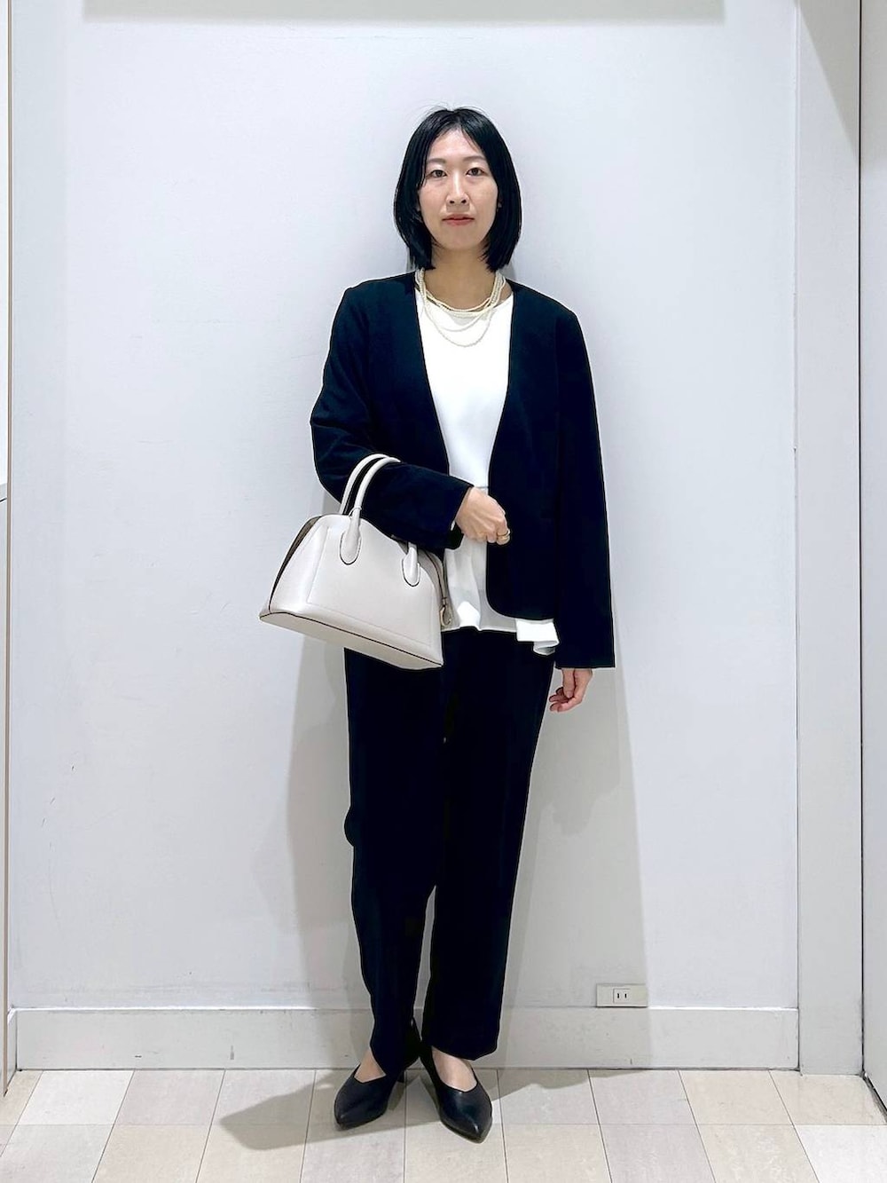 ホワイト系のショルダーバッグ、ブルー系のセットアップ、ブラック系のパンプスを着用したレディースの冬コーディネートの5枚目の写真