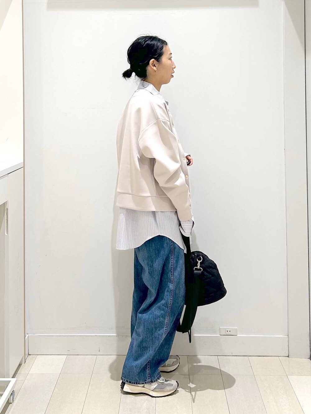 ブラック系のハンドバッグ、ブルー系のデニムパンツ、ピンク系のカーディガン/ボレロを着用したレディースの春コーディネートの2枚目の写真