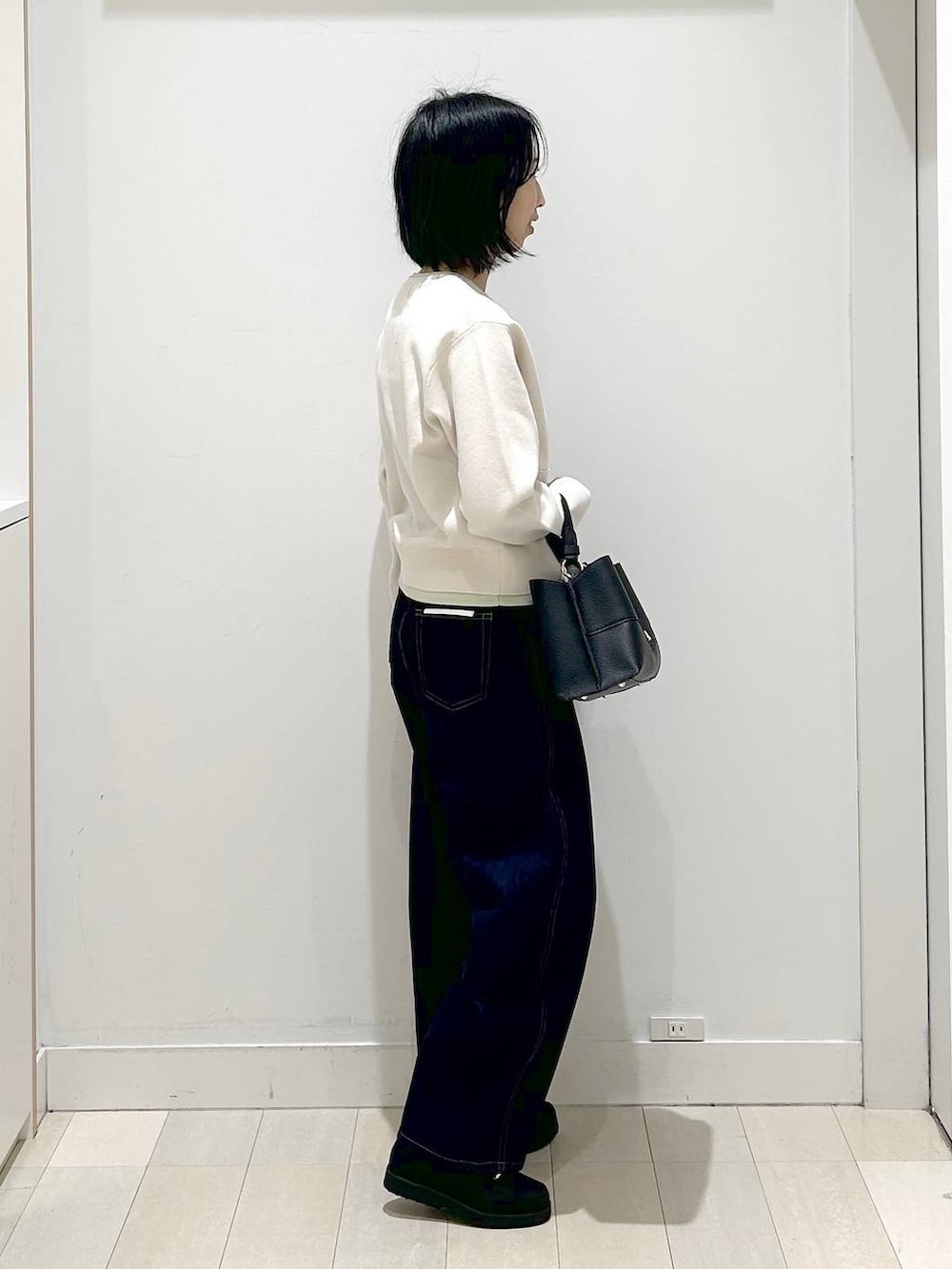 ブラック系のローファー、ブラック系のショルダーバッグ、ブルー系のデニムパンツを着用したレディースの冬コーディネートの4枚目の写真