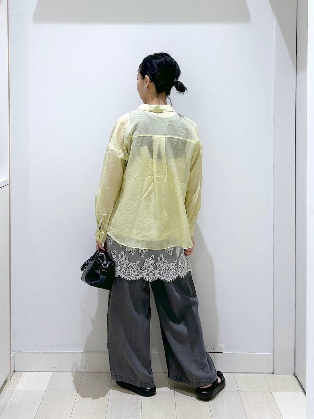 イエロー系のシャツ/ブラウス、ホワイト系のキャミソール、ブラック系のデニムパンツを着用したレディースの春コーディネートの3枚目の写真