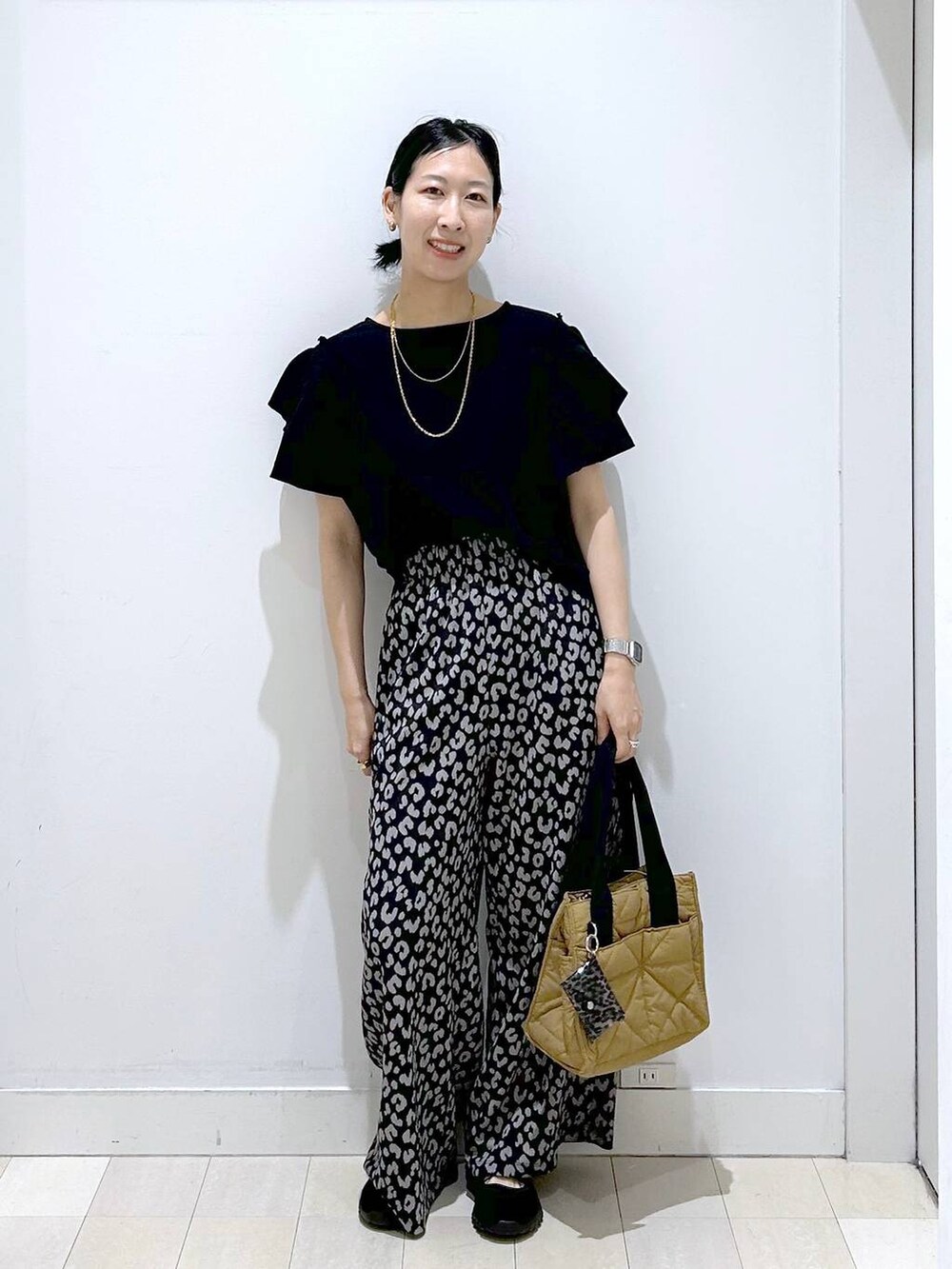 ブラウン系のトートバッグ、その他のその他パンツ、ブラック系のスニーカーを着用したレディースの春コーディネートの5枚目の写真