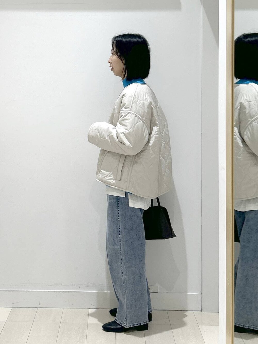 ブラウン系のショルダーバッグ、ベージュ系のブルゾン、ブルー系のデニムパンツを着用したレディースの冬コーディネートの4枚目の写真