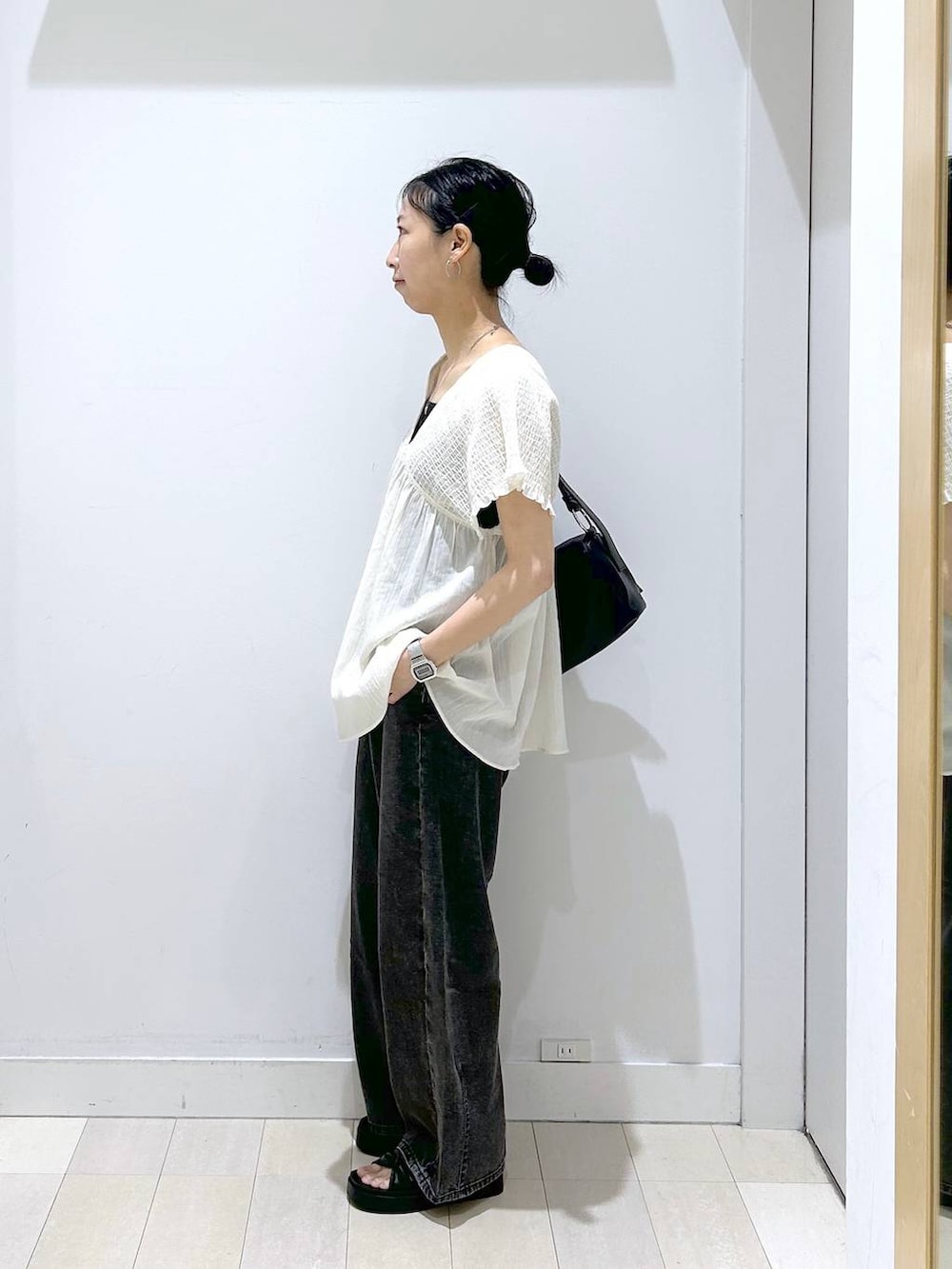 ブラック系のデニムパンツ、ベージュ系のシャツ/ブラウス、ブラック系のサンダルを着用したレディースの夏コーディネートの2枚目の写真