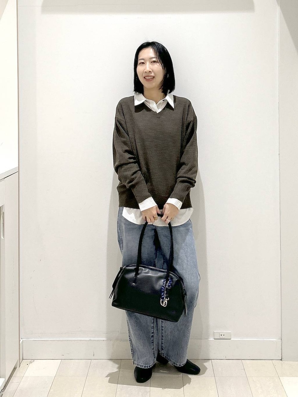 ブラック系のボストンバッグ、ブルー系のデニムパンツ、その他のシャツ/ブラウスを着用したレディースの冬コーディネートの5枚目の写真