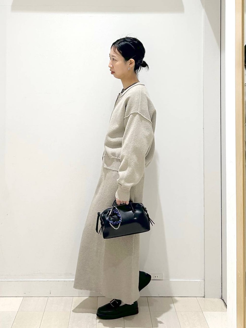 ブラック系のローファー、ベージュ系のワンピース、グレー系のTシャツ/カットソーを着用したレディースの春コーディネートの2枚目の写真