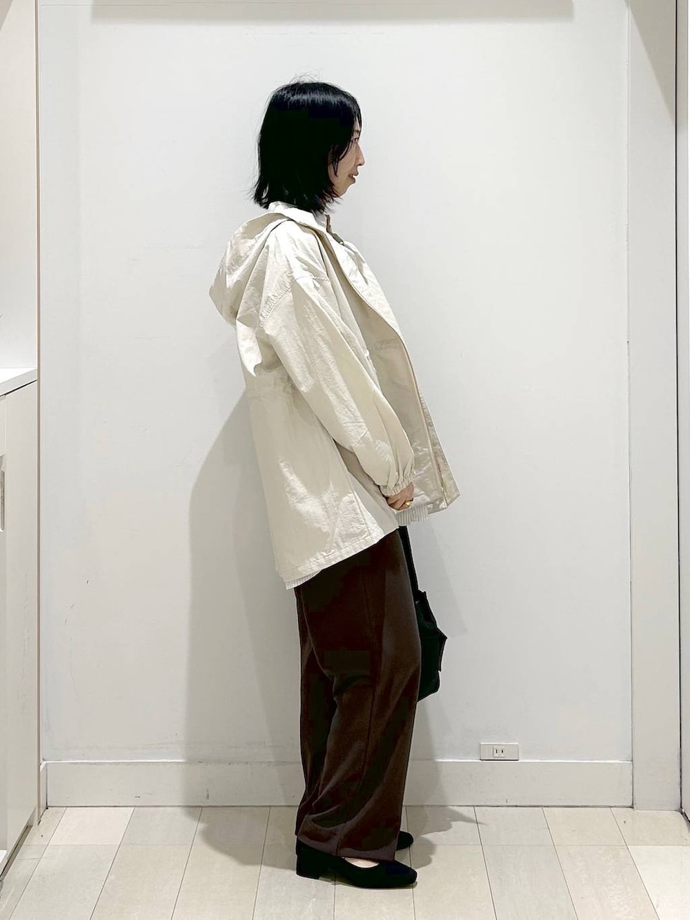 ブラック系のトートバッグ、ベージュ系のパーカー、ブラウン系のその他パンツを着用したレディースの春コーディネートの2枚目の写真