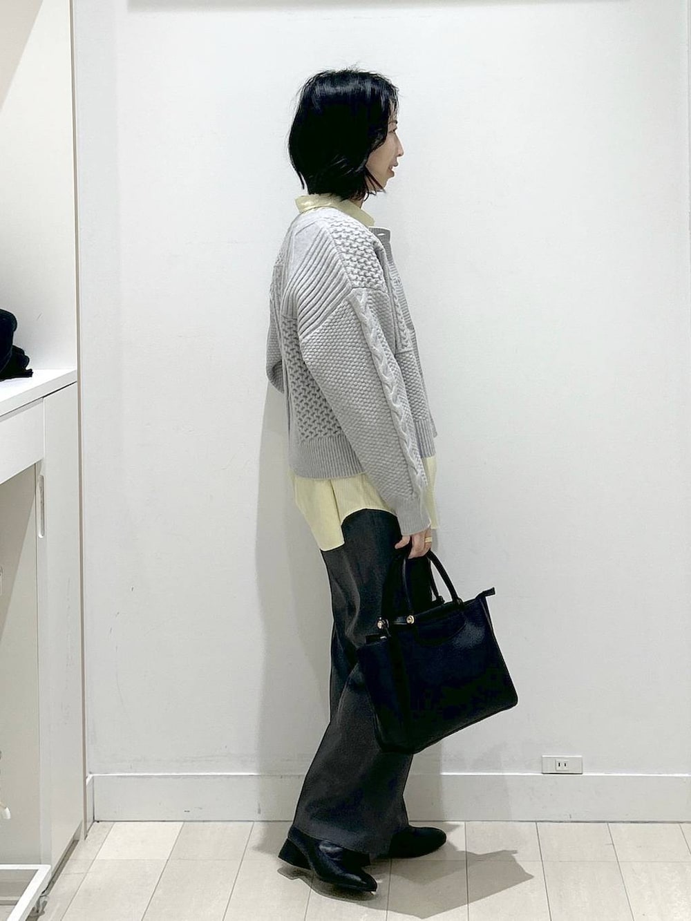 イエロー系のシャツ/ブラウス、グレー系のスラックス、ブラック系のブーツを着用したレディースの冬コーディネートの2枚目の写真