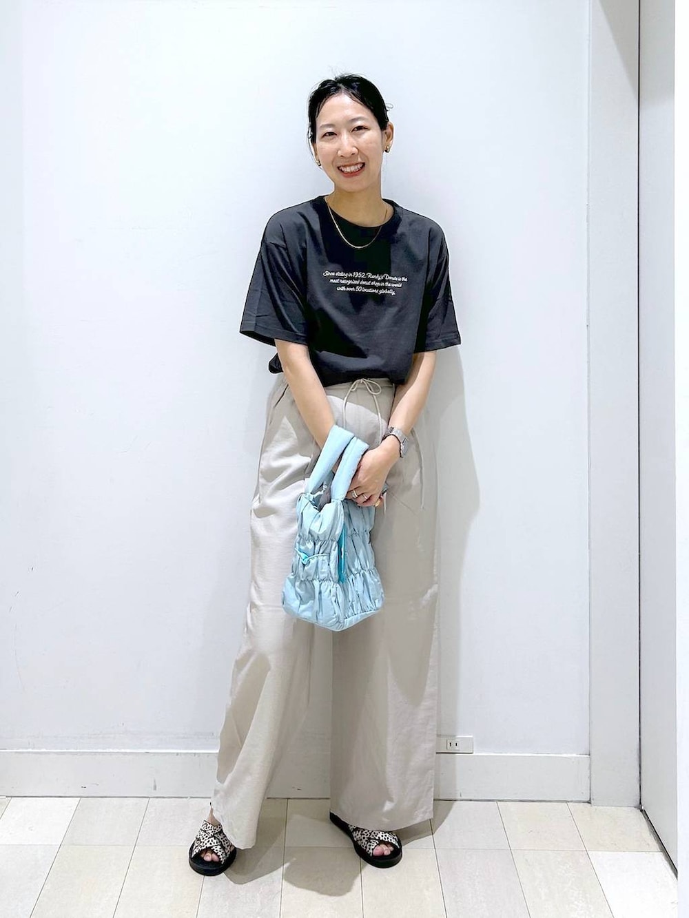 ブルー系のトートバッグ、ベージュ系のその他パンツ、ブラック系のサンダルを着用したレディースの夏コーディネートの2枚目の写真