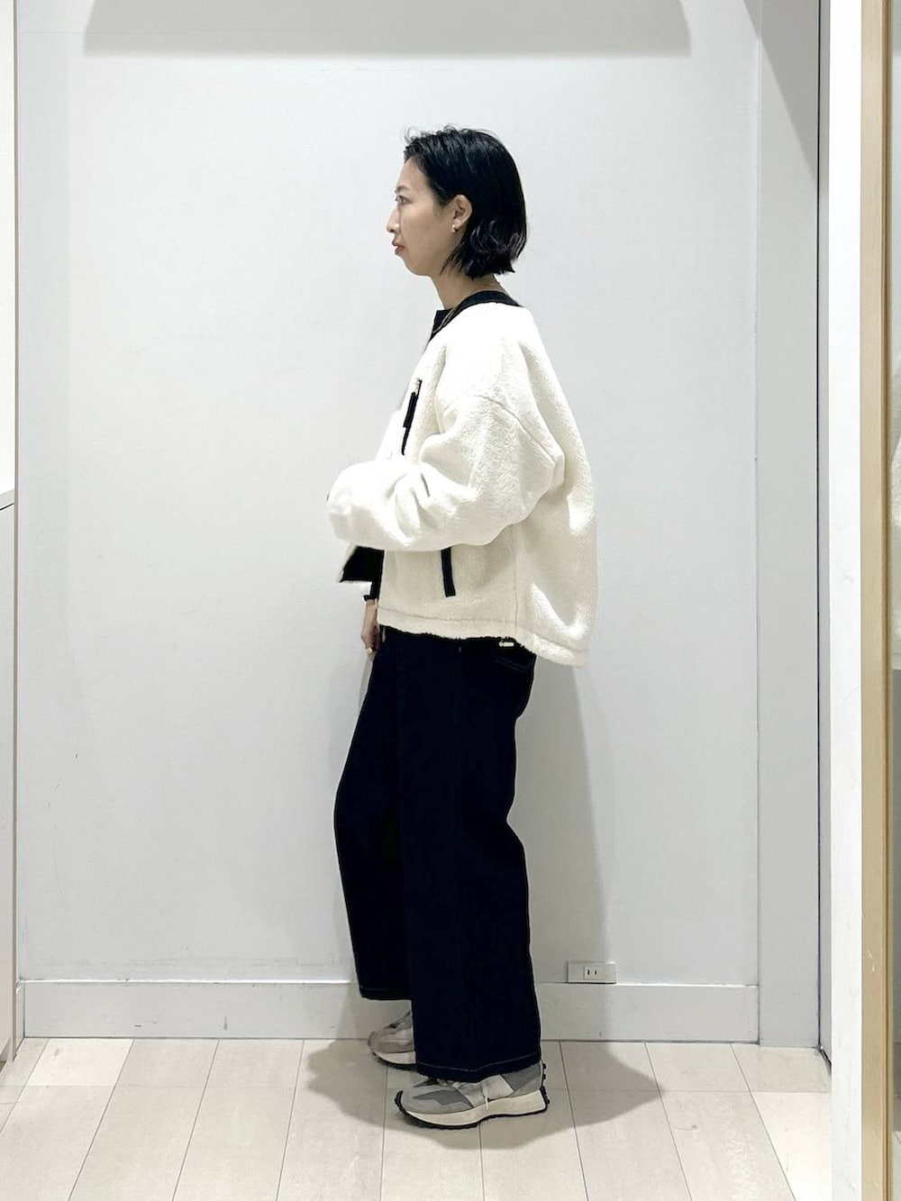 ブラック系のニット/セーター、ホワイト系のブルゾン、ブルー系のデニムパンツを着用したレディースの秋コーディネートの4枚目の写真