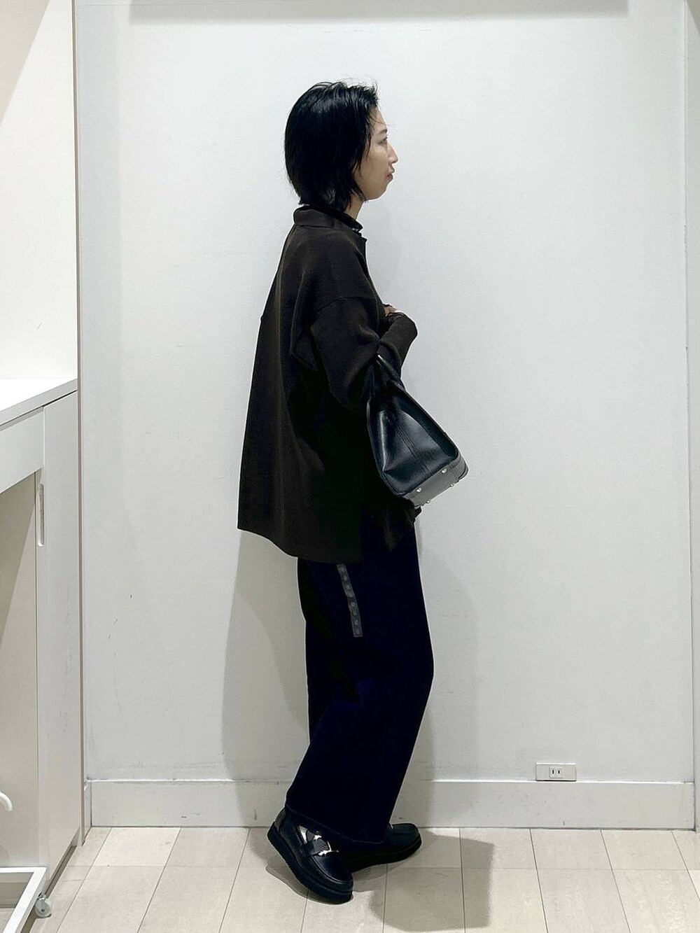 ブラック系のローファー、ブルー系のデニムパンツ、ブラック系のショルダーバッグを着用したレディースの秋コーディネートの2枚目の写真