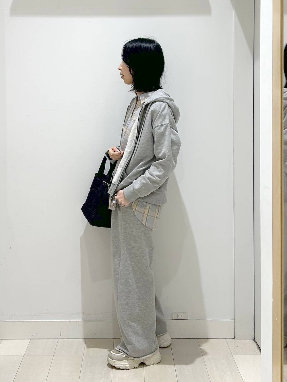 ブラック系のトートバッグ、ブルー系のシャツ/ブラウス、グレー系のパーカーを着用したレディースの春コーディネートの2枚目の写真