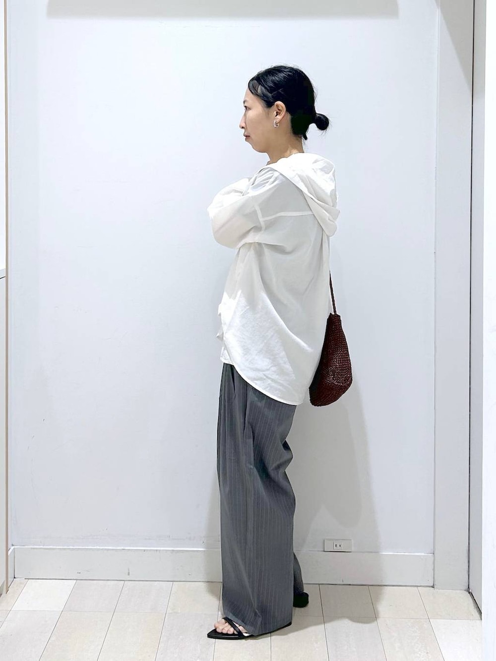 グレー系のその他パンツ、ホワイト系のTシャツ/カットソー、ブラウン系のクラッチバッグを着用したレディースの夏コーディネートの2枚目の写真
