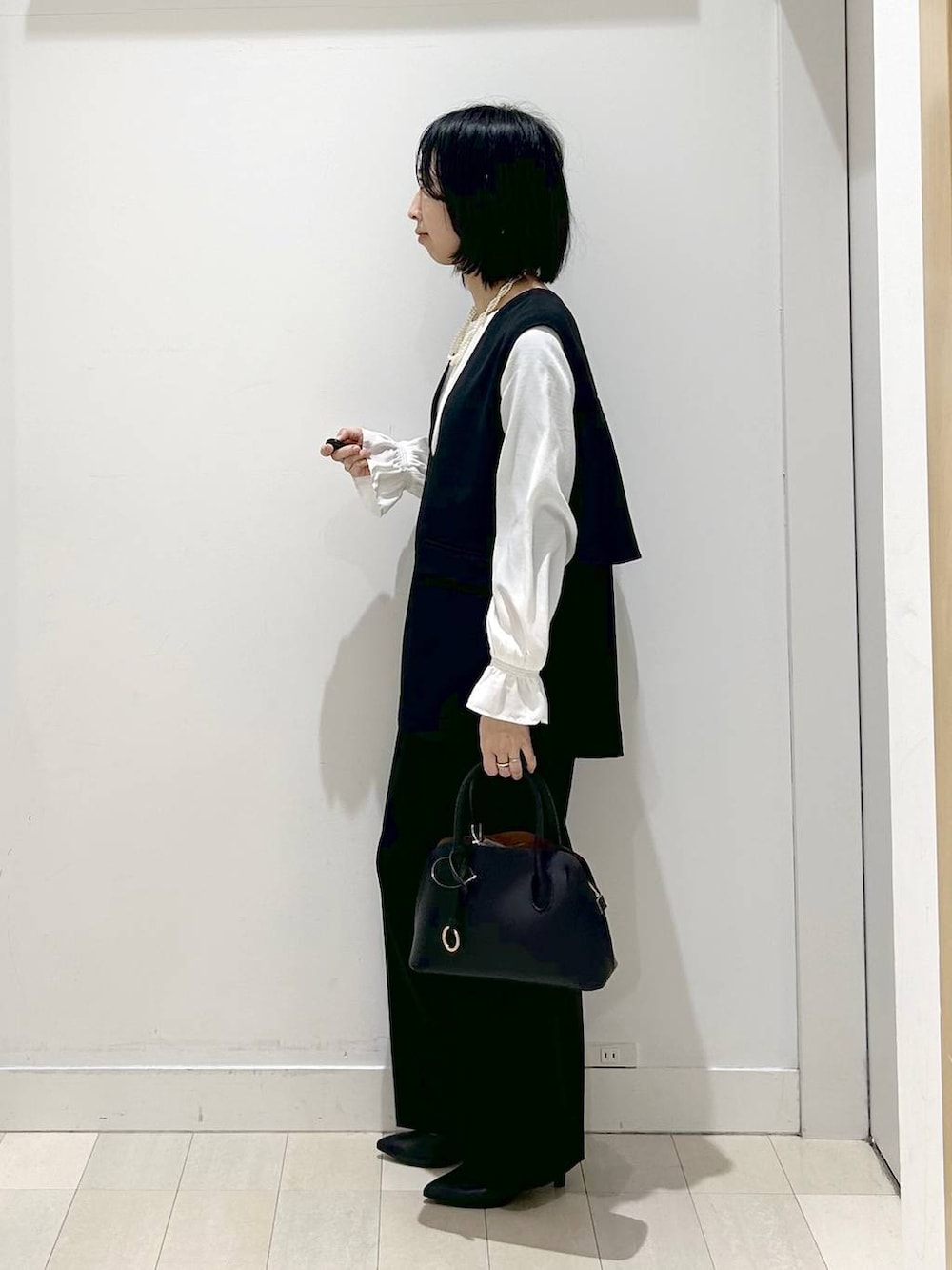 ブラック系のショルダーバッグ、ブラック系のパンプス、ブラック系のセットアップを着用したレディースの冬コーディネートの2枚目の写真