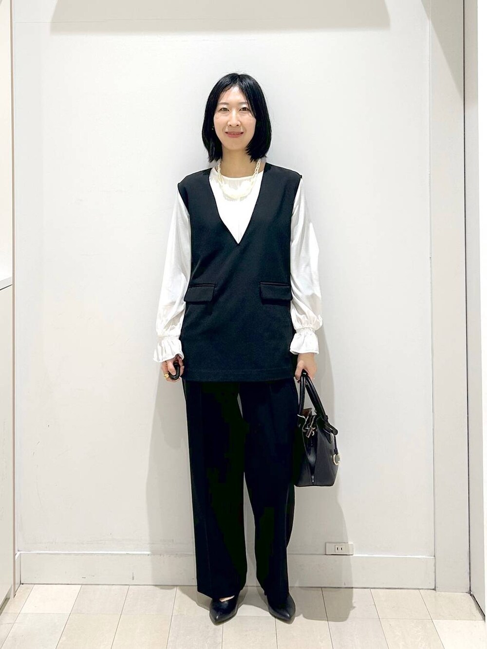 ブラック系のショルダーバッグ、ブラック系のパンプス、ブラック系のセットアップを着用したレディースの冬コーディネートの5枚目の写真