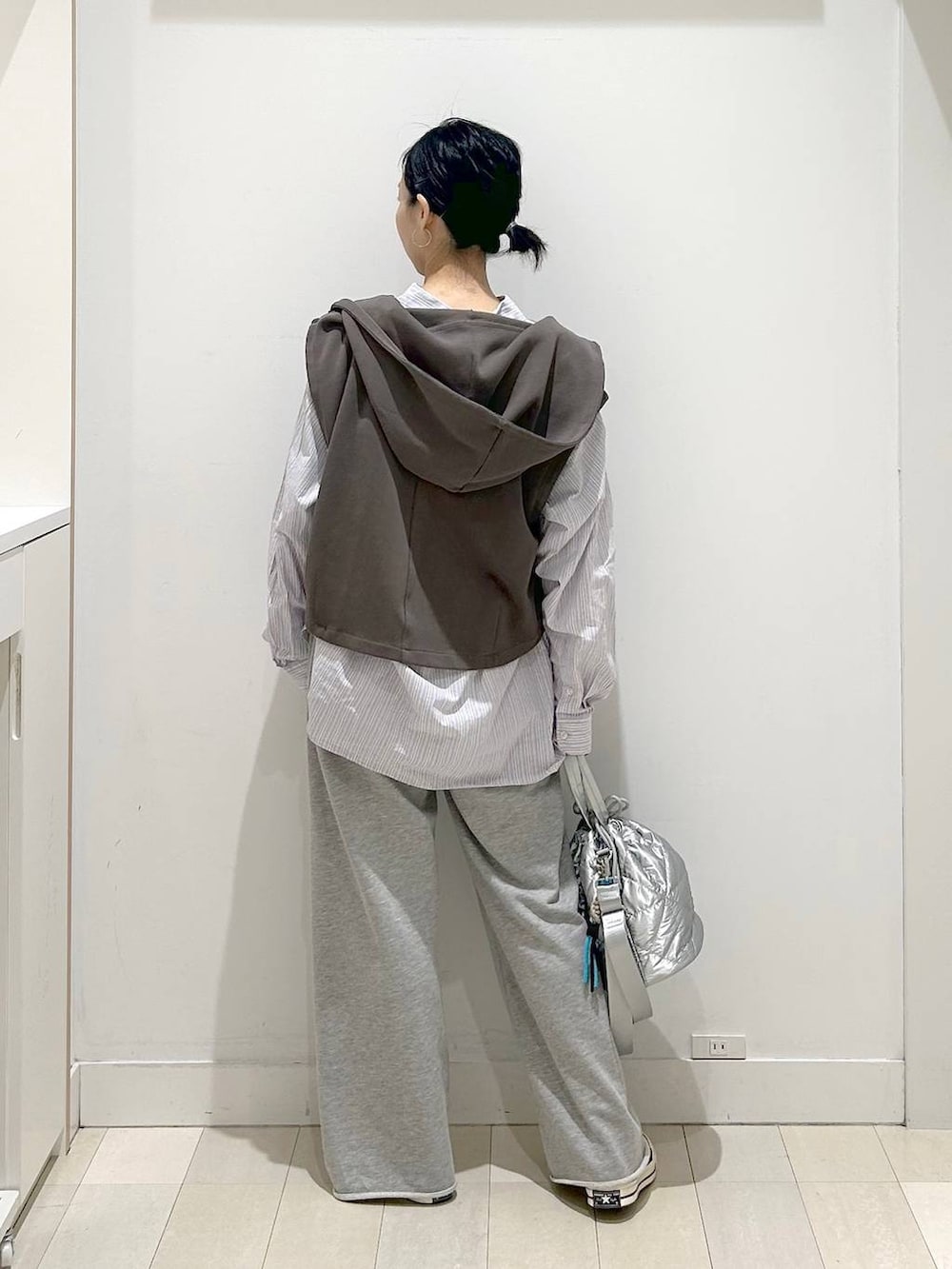 シルバー系のハンドバッグ、グレー系のスウェットパンツ、ブラウン系のベストを着用したレディースの春コーディネートの3枚目の写真