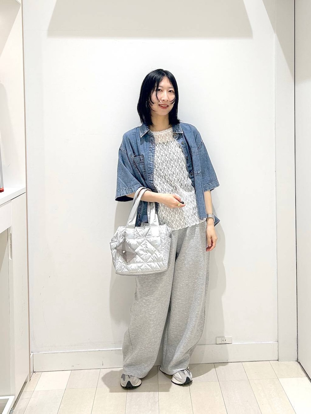 シルバー系のトートバッグ、ホワイト系のTシャツ/カットソー、ブルー系のシャツ/ブラウスを着用したレディースの春コーディネートの5枚目の写真