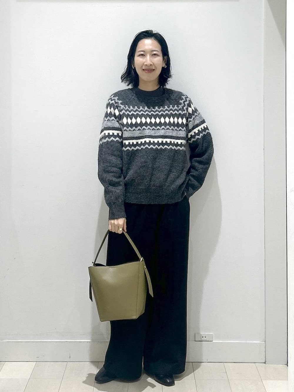 グリーン系のショルダーバッグ、グレー系のニット/セーター、ブラック系のその他パンツを着用したレディースの冬コーディネートの5枚目の写真