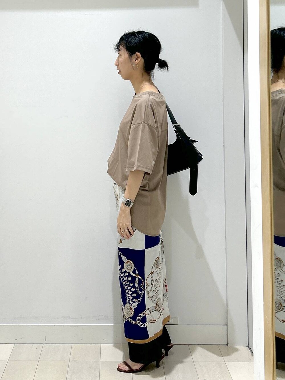 ブルー系のデニムパンツ、ブラック系のショルダーバッグ、ベージュ系のTシャツ/カットソーを着用したレディースの夏コーディネートの4枚目の写真