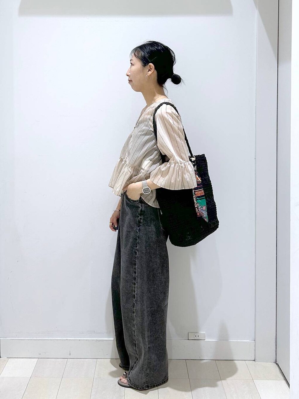 ブラック系のデニムパンツ、ブラック系のトートバッグ、ベージュ系のカーディガン/ボレロを着用したレディースの夏コーディネートの2枚目の写真