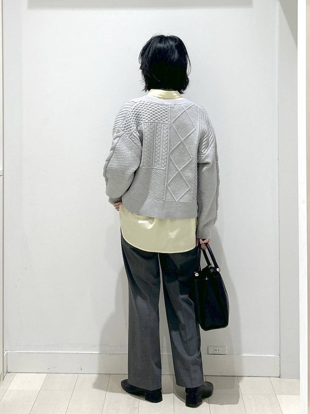 イエロー系のシャツ/ブラウス、グレー系のスラックス、ブラック系のブーツを着用したレディースの冬コーディネートの3枚目の写真