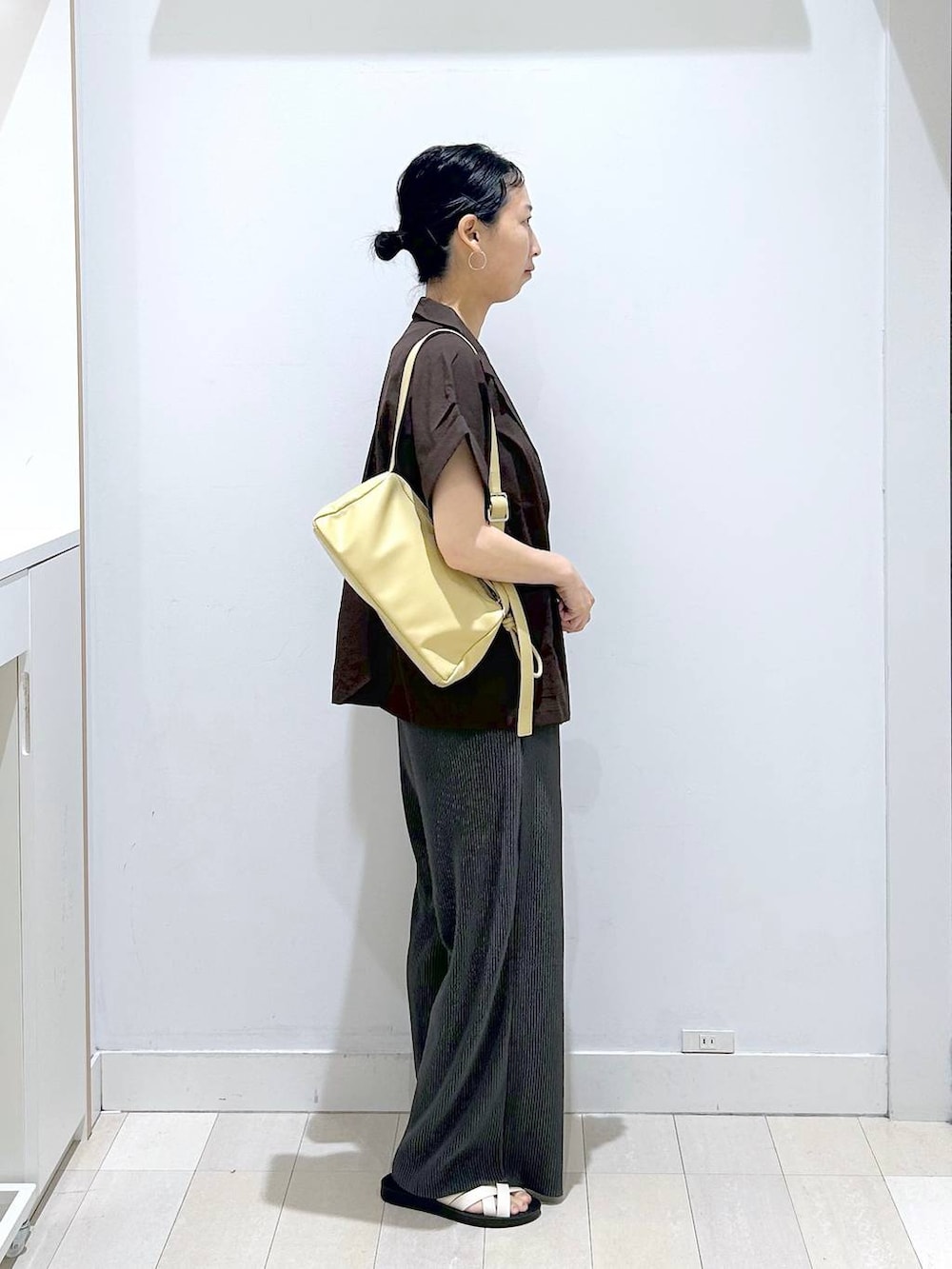 イエロー系のショルダーバッグ、ホワイト系のタンクトップ、ブラック系のその他パンツを着用したレディースの夏コーディネートの4枚目の写真