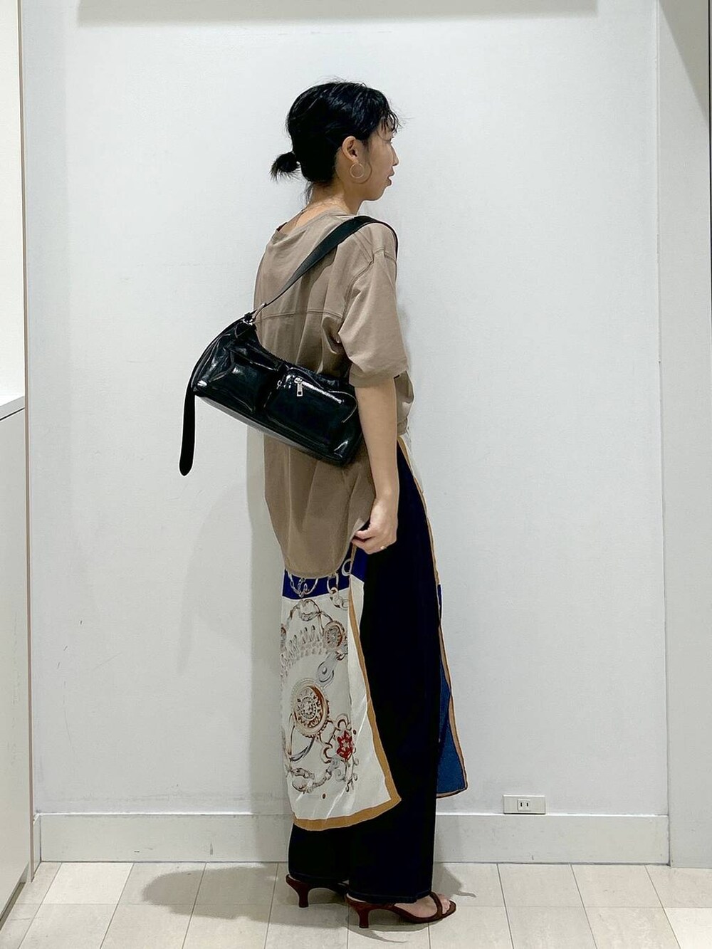 ブルー系のデニムパンツ、ブラック系のショルダーバッグ、ベージュ系のTシャツ/カットソーを着用したレディースの夏コーディネートの2枚目の写真