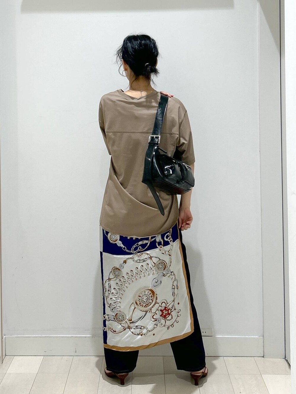 ブルー系のデニムパンツ、ブラック系のショルダーバッグ、ベージュ系のTシャツ/カットソーを着用したレディースの夏コーディネートの3枚目の写真