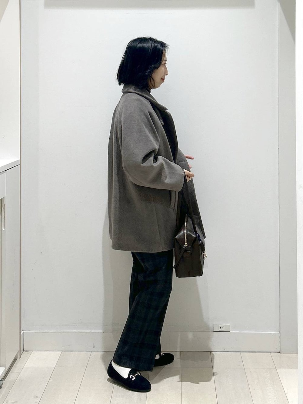 ブラウン系のボストンバッグ、ブラウン系のチェスターコート、ブラック系のその他パンツを着用したレディースの冬コーディネートの2枚目の写真