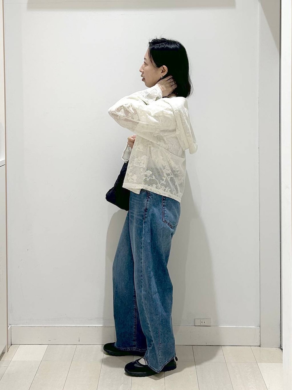 ブラック系のトートバッグ、ブルー系のデニムパンツ、ベージュ系のパーカーを着用したレディースの春コーディネートの2枚目の写真
