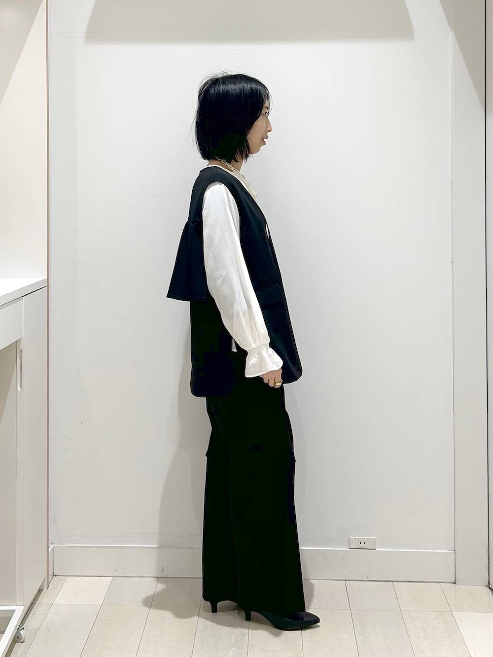 ブラック系のショルダーバッグ、ブラック系のパンプス、ブラック系のセットアップを着用したレディースの冬コーディネートの4枚目の写真