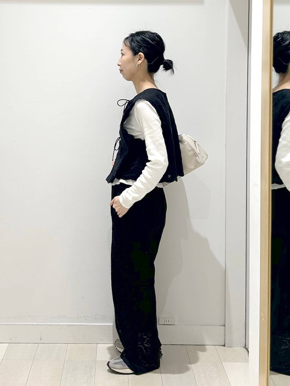 ブラック系のベスト、ブラック系のその他パンツ、ベージュ系のショルダーバッグを着用したレディースの春コーディネートの2枚目の写真