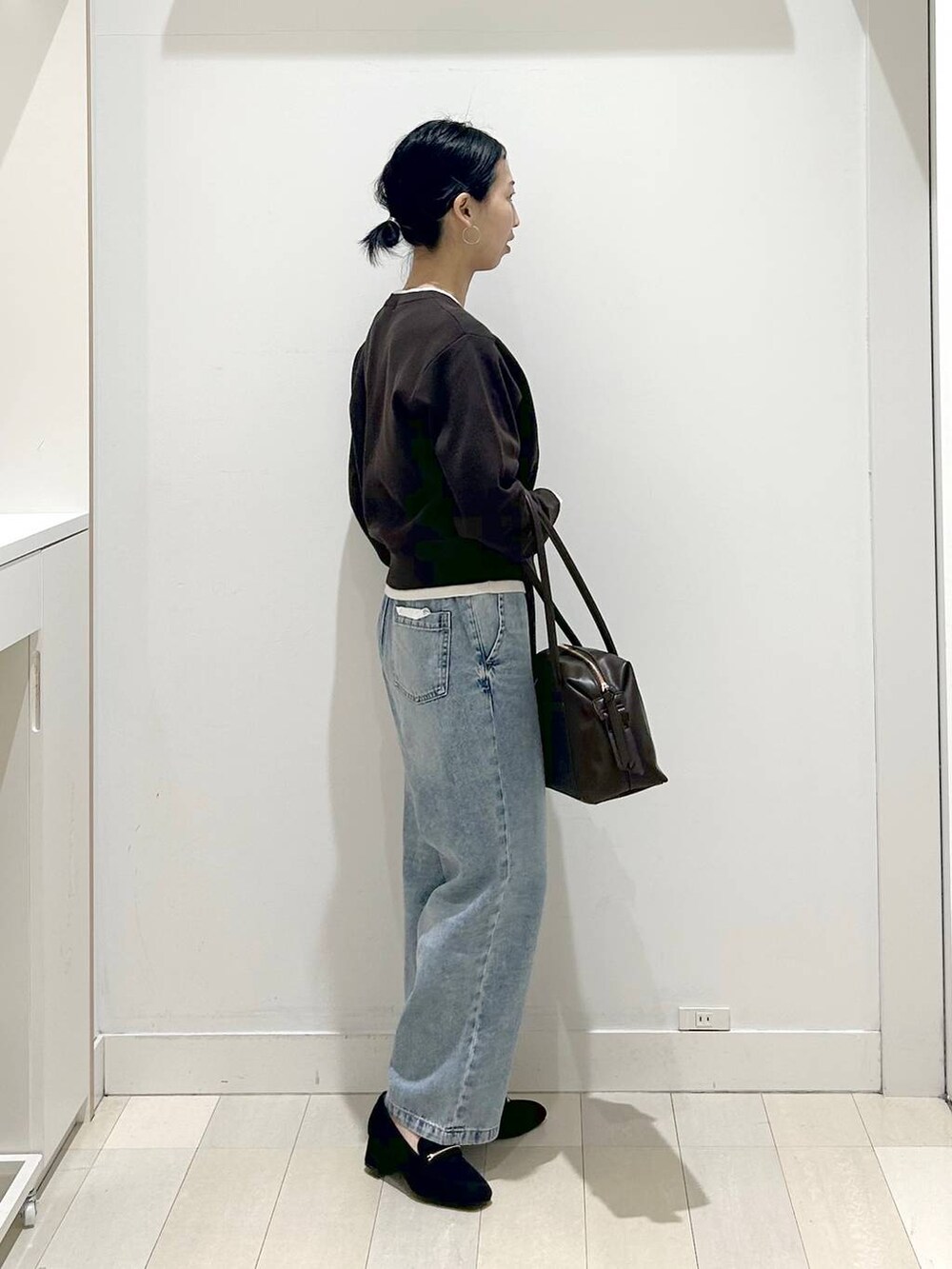 ブラック系のローファー、ブラック系のボストンバッグ、ブルー系のデニムパンツを着用したレディースの春コーディネートの2枚目の写真