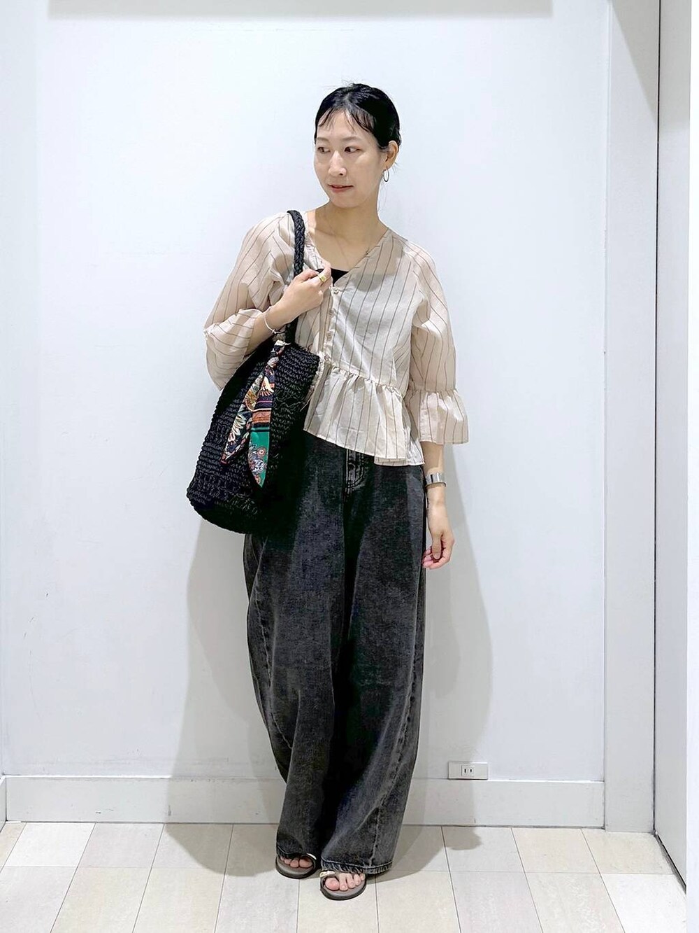 ブラック系のデニムパンツ、ブラック系のトートバッグ、ベージュ系のカーディガン/ボレロを着用したレディースの夏コーディネートの5枚目の写真