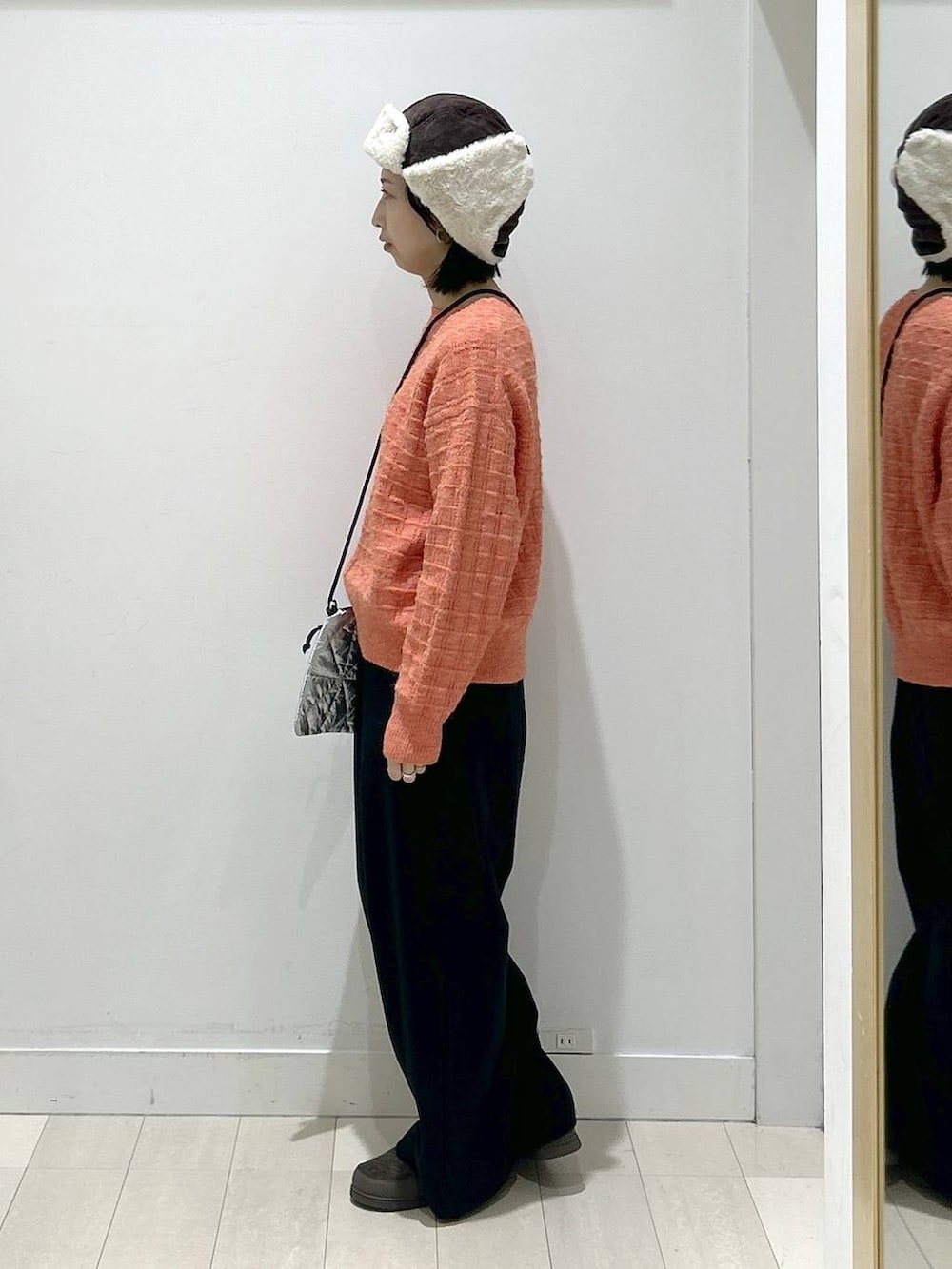 オレンジ系のニット/セーター、ブラック系のその他パンツ、グレー系のショルダーバッグを着用したレディースの冬コーディネートの4枚目の写真