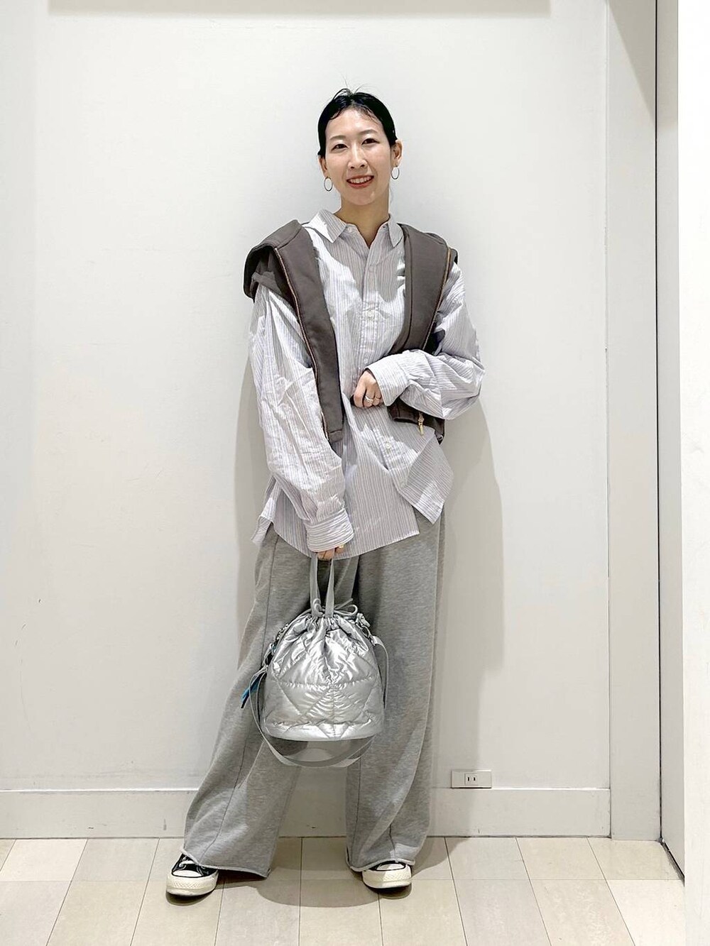 シルバー系のハンドバッグ、グレー系のスウェットパンツ、ブラウン系のベストを着用したレディースの春コーディネートの5枚目の写真