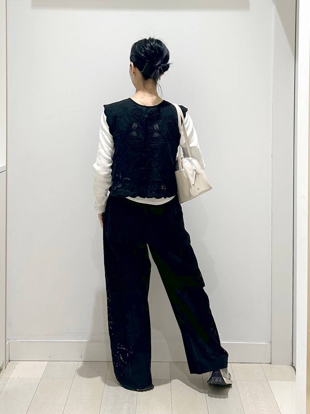 ブラック系のベスト、ブラック系のその他パンツ、ベージュ系のショルダーバッグを着用したレディースの春コーディネートの3枚目の写真