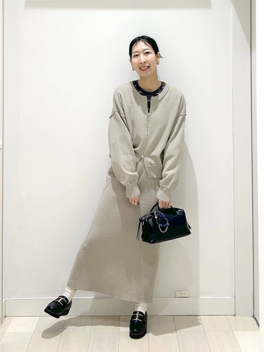 ブラック系のローファー、ベージュ系のワンピース、グレー系のTシャツ/カットソーを着用したレディースの春コーディネートの5枚目の写真