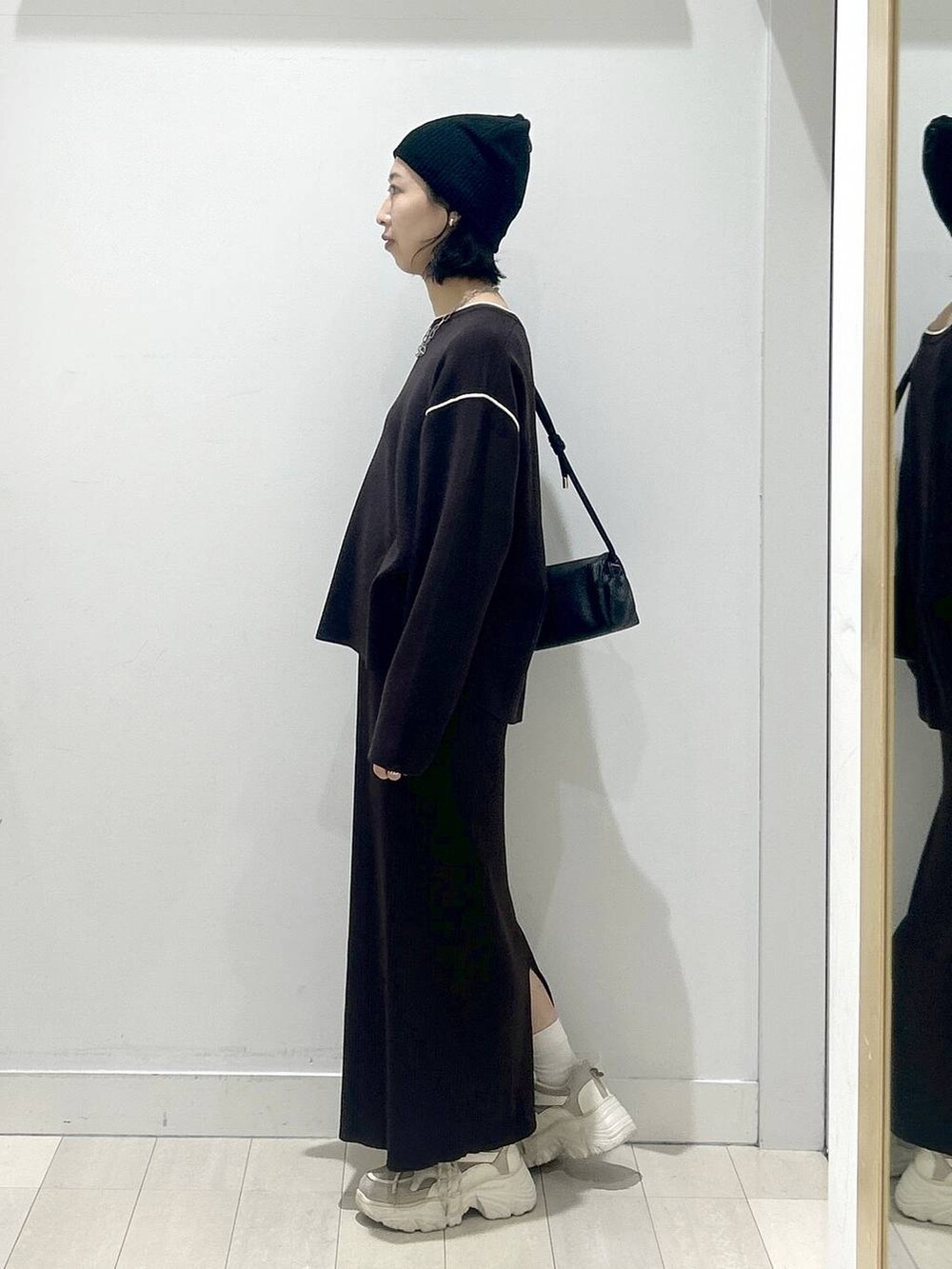 ブラック系のショルダーバッグ、ブラウン系のワンピースを着用したレディースの冬コーディネートの4枚目の写真