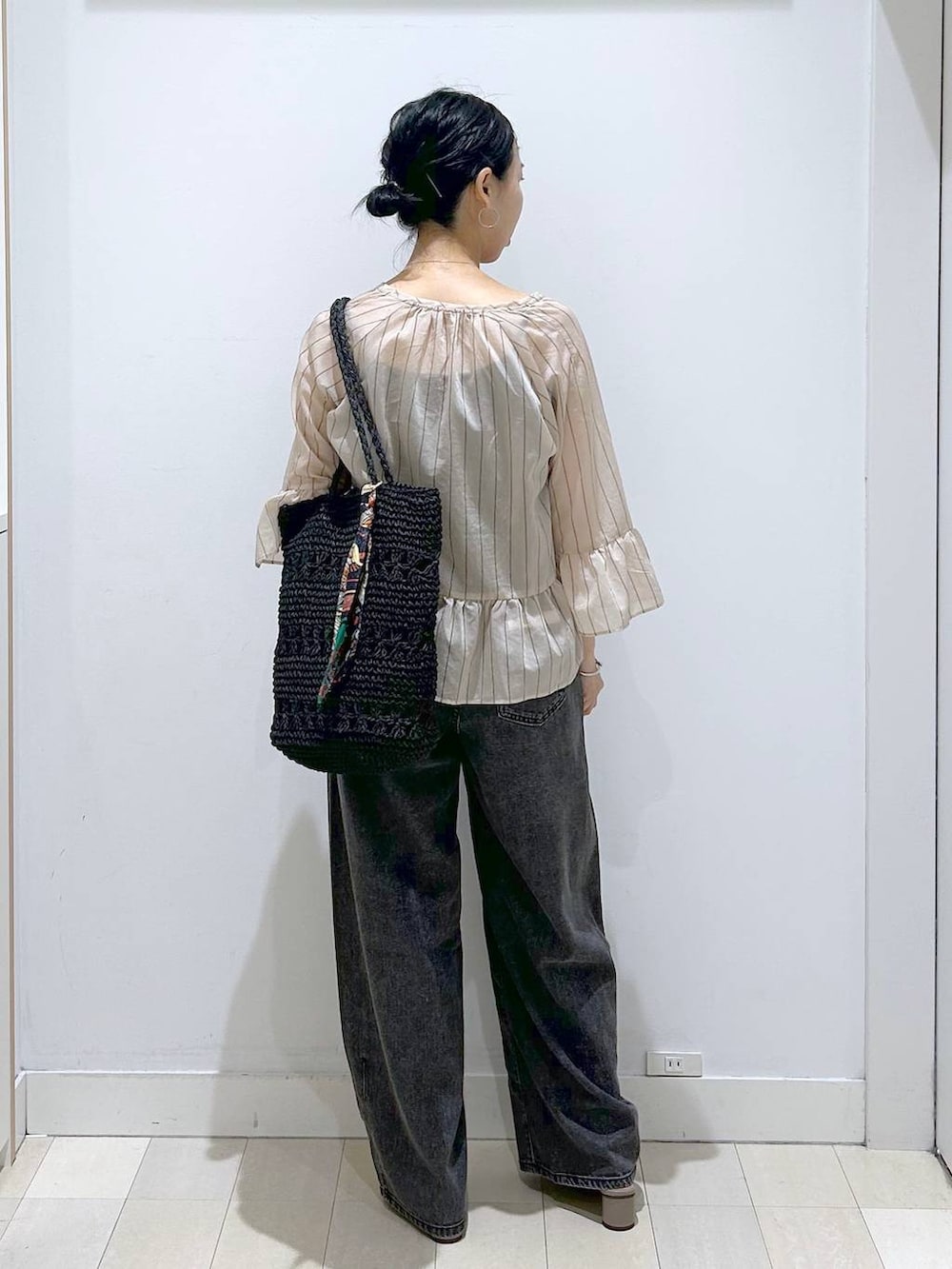 ブラック系のデニムパンツ、ブラック系のトートバッグ、ベージュ系のカーディガン/ボレロを着用したレディースの夏コーディネートの3枚目の写真