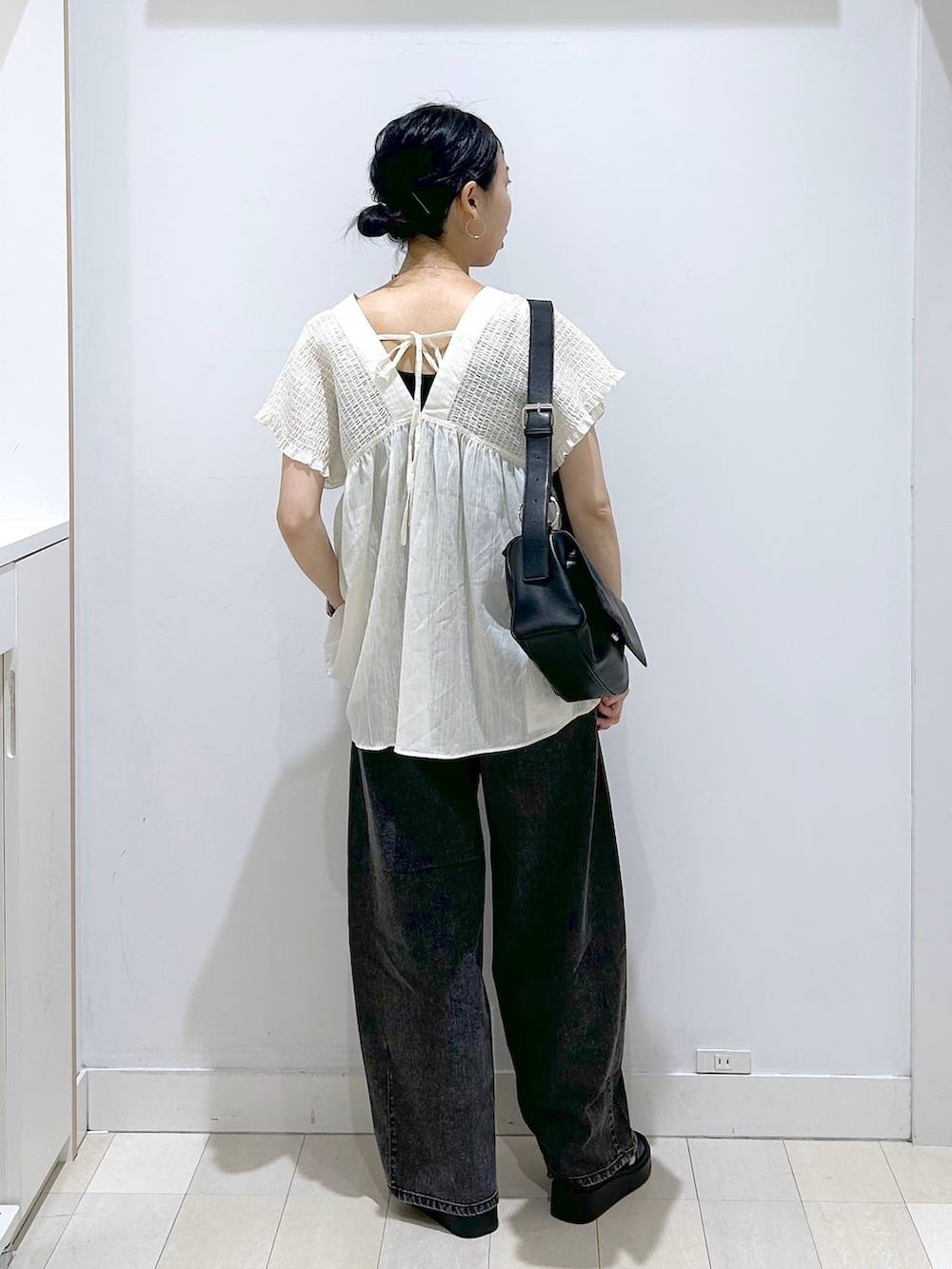 ブラック系のデニムパンツ、ベージュ系のシャツ/ブラウス、ブラック系のサンダルを着用したレディースの夏コーディネートの3枚目の写真