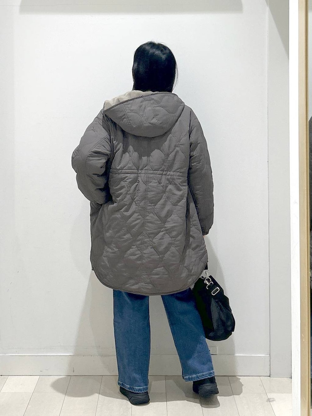 ブラック系のショルダーバッグ、ブラウン系のブルゾン、ホワイト系のTシャツ/カットソーを着用したレディースの冬コーディネートの3枚目の写真