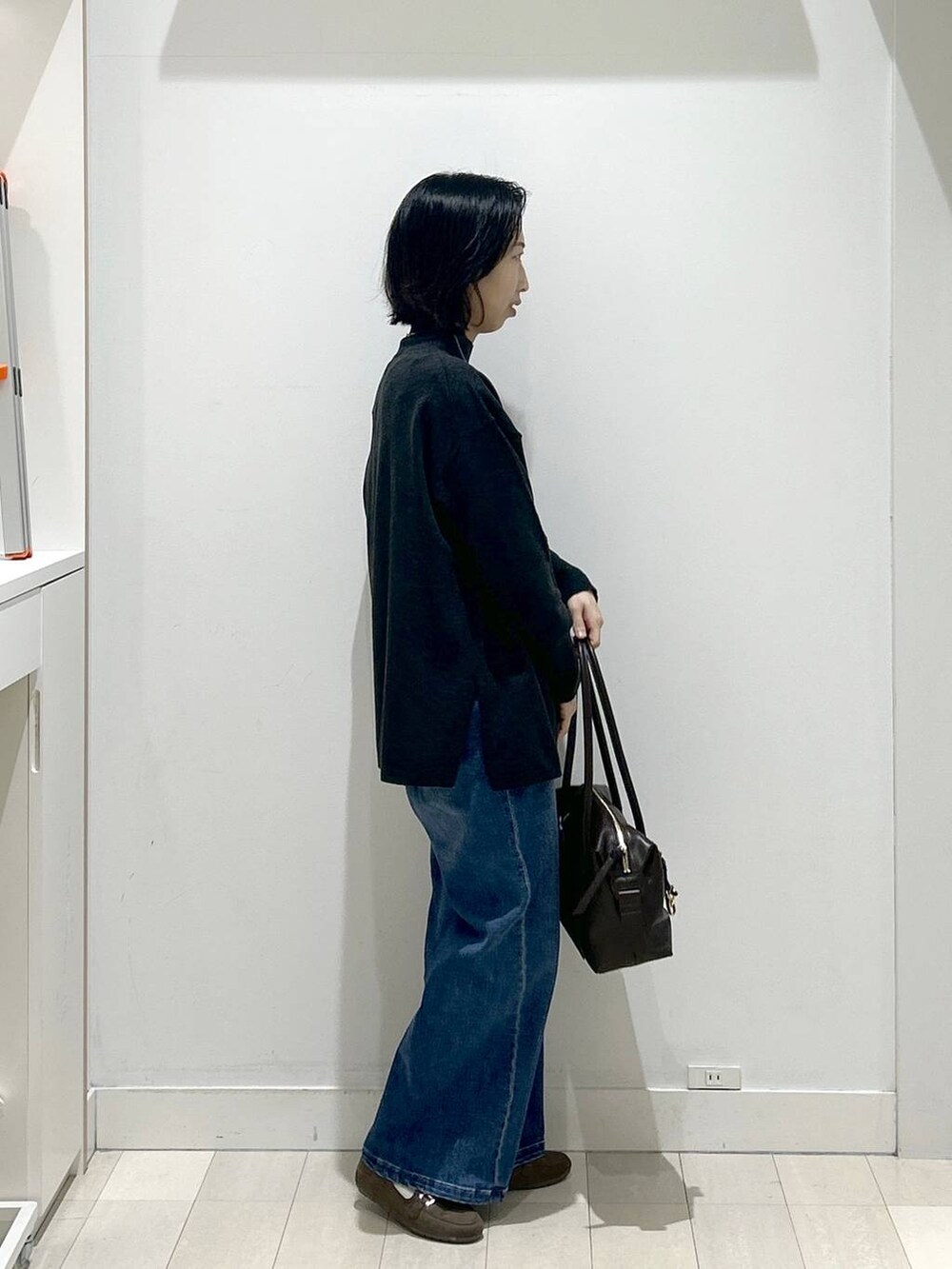 ブラウン系のボストンバッグ、グレー系のニット/セーター、ブラウン系のローファーを着用したレディースの冬コーディネートの2枚目の写真