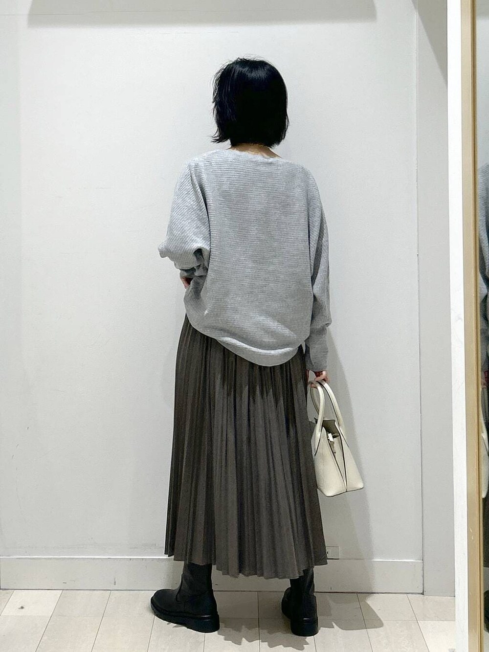 ホワイト系のショルダーバッグ、ブラック系のブーツ、グレー系のスカートを着用したレディースの冬コーディネートの3枚目の写真