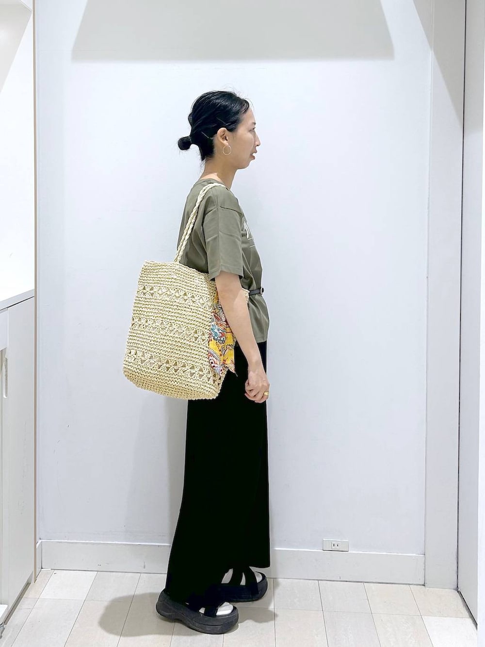 グリーン系のTシャツ/カットソー、ベージュ系のトートバッグ、ブラック系のスカートを着用したレディースの夏コーディネートの4枚目の写真